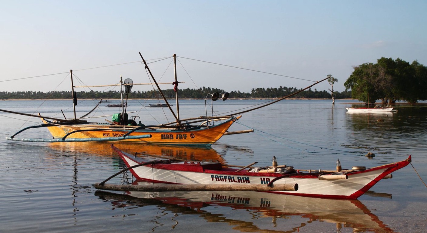 Traditional outrigger bangka boats moored in shallow coastal water in the Philippines
